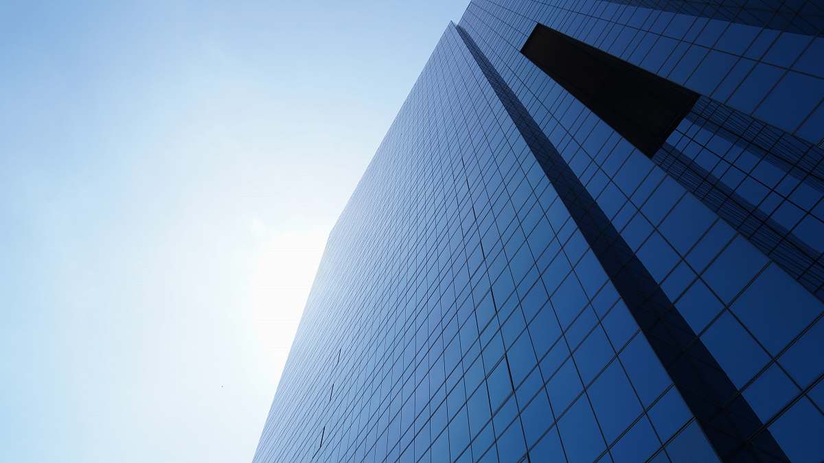 high rise tall blue glass paneled building under clear blue sky town